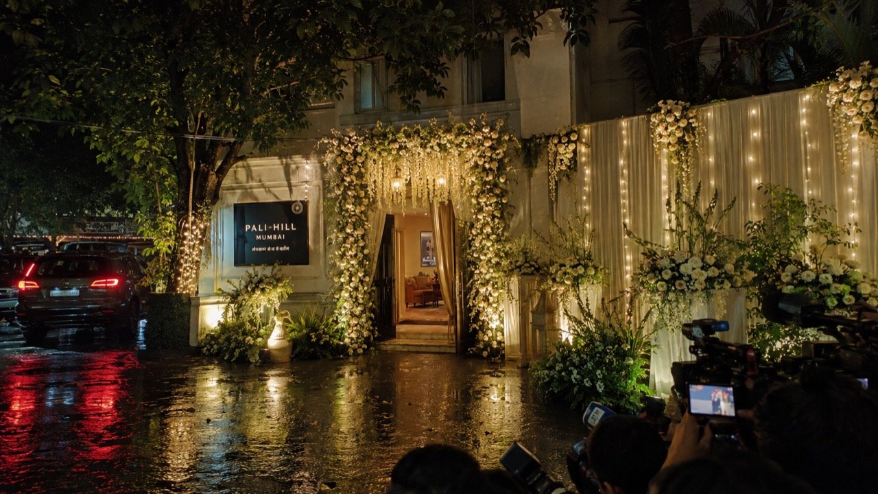 A Mumbai bungalow decorated with fairy lights, marigold garlands and wedding tents on a rainy evening as guests arrive for an intimate Bollywood home wedding