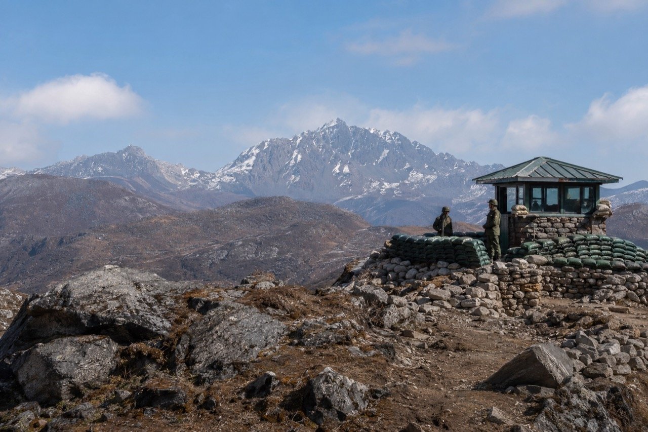 Indian Army soldiers patrolling a rugged, mist-covered Himalayan mountain ridge along the border in Arunachal Pradesh