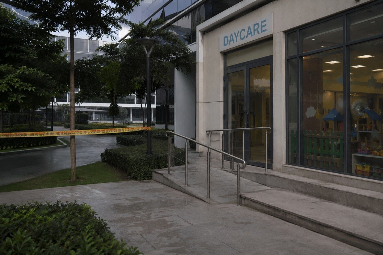 Exterior of a corporate office campus daycare centre in Bengaluru with a police vehicle parked outside, seen in muted evening light
