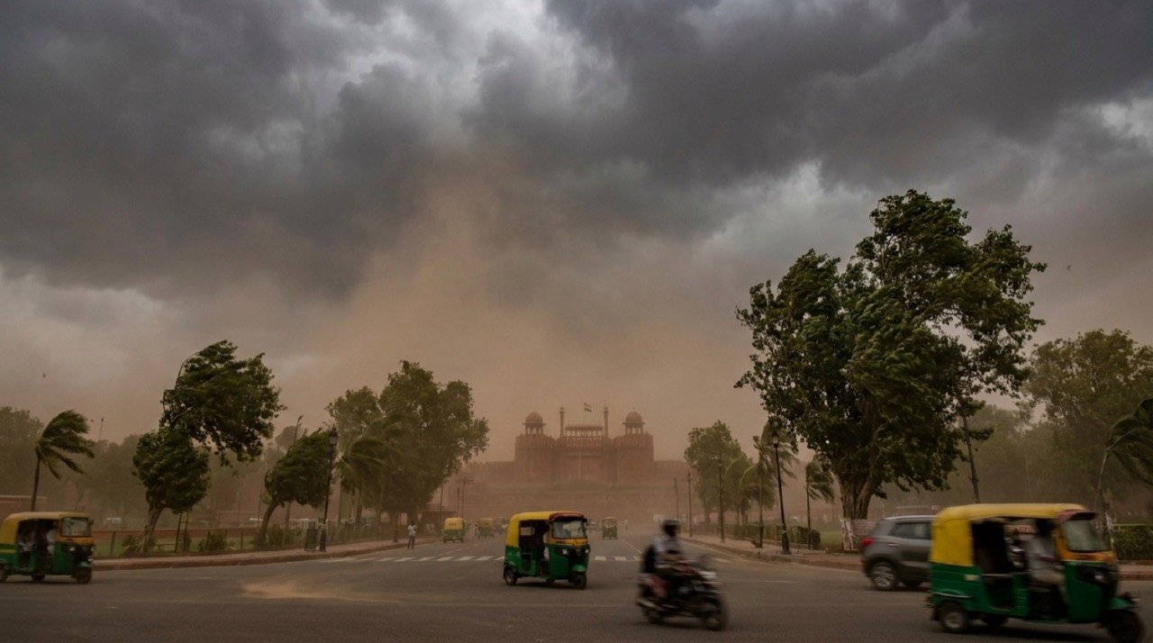 Dark storm clouds and dust haze over the Delhi skyline as strong winds bend trees during a red alert weather warning