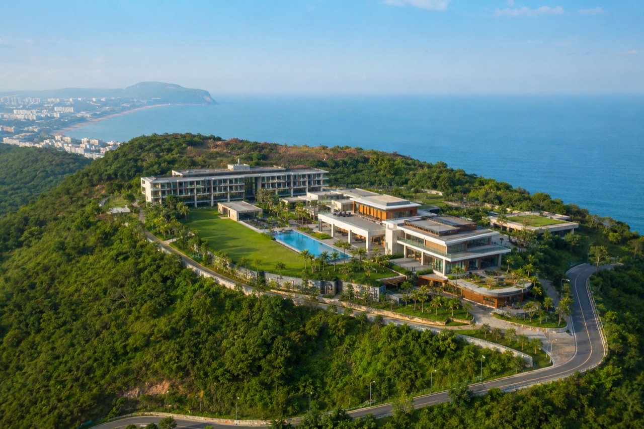 A sprawling modern building complex on a green coastal hill overlooking the Bay of Bengal at Rushikonda, Visakhapatnam