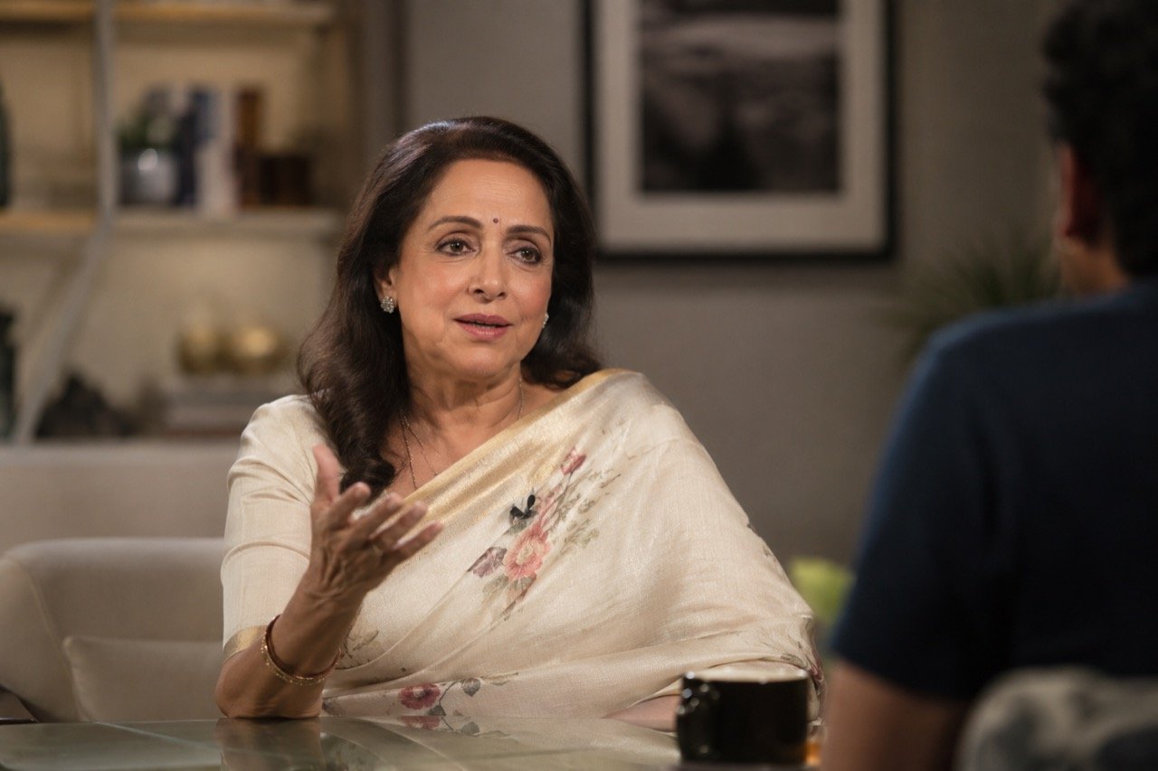 An elegant veteran Bollywood actress speaking at an interview, with warm studio lighting and a backdrop suggesting a candid conversation about relationships